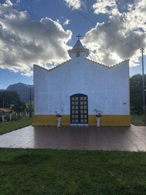 Capela serrana com céu azul e nuvens