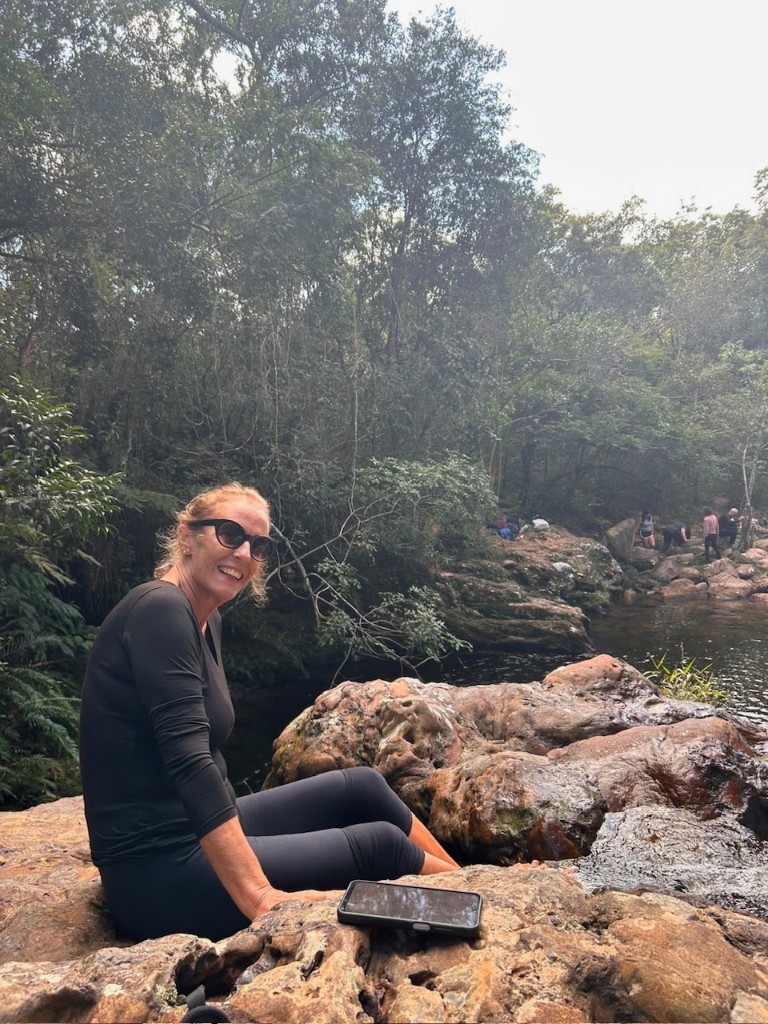 Trilheira à beira do rio em meio à mata